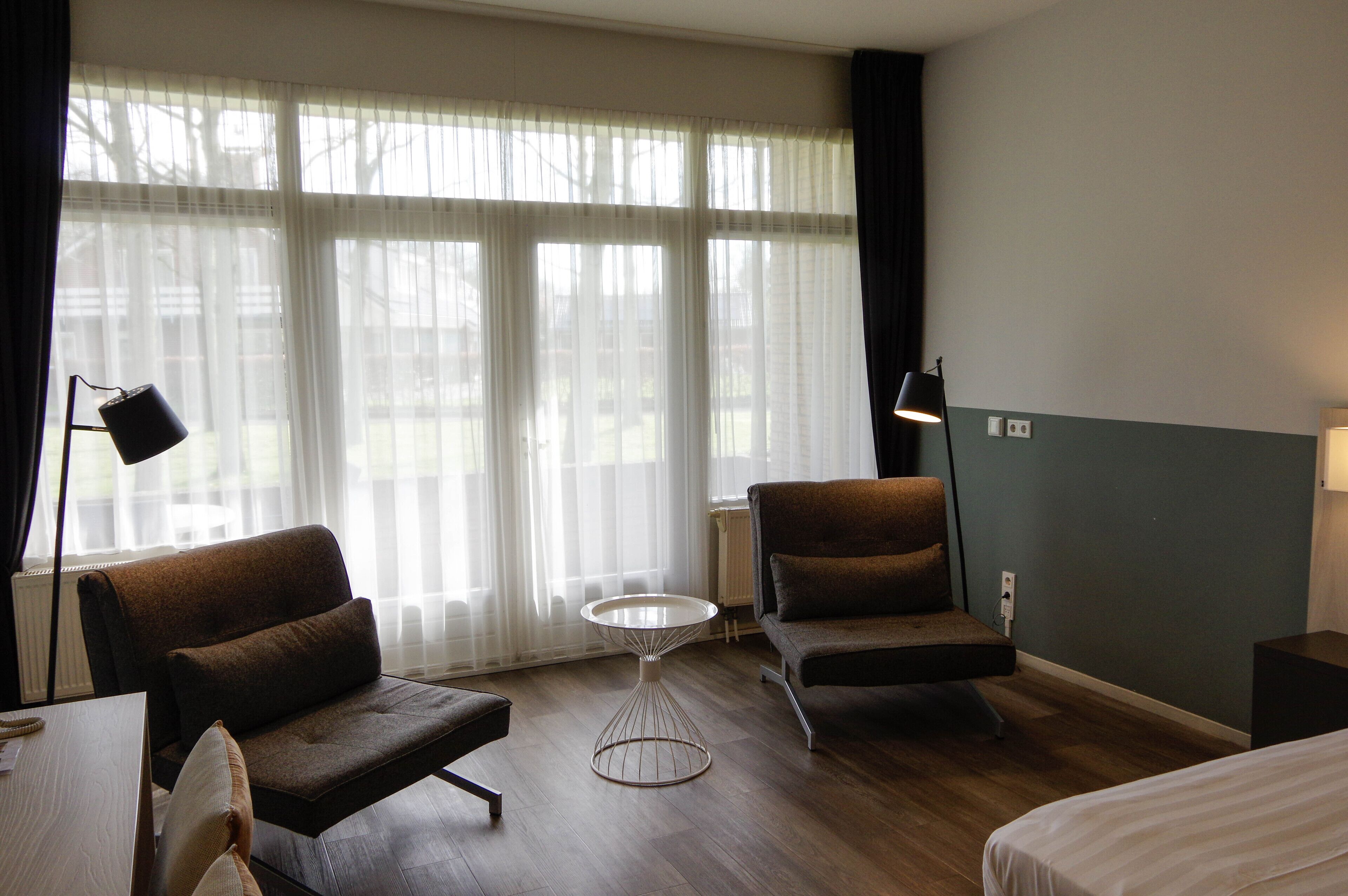 Ett hotellrum med två soffor, ett litet runt bord och en säng.