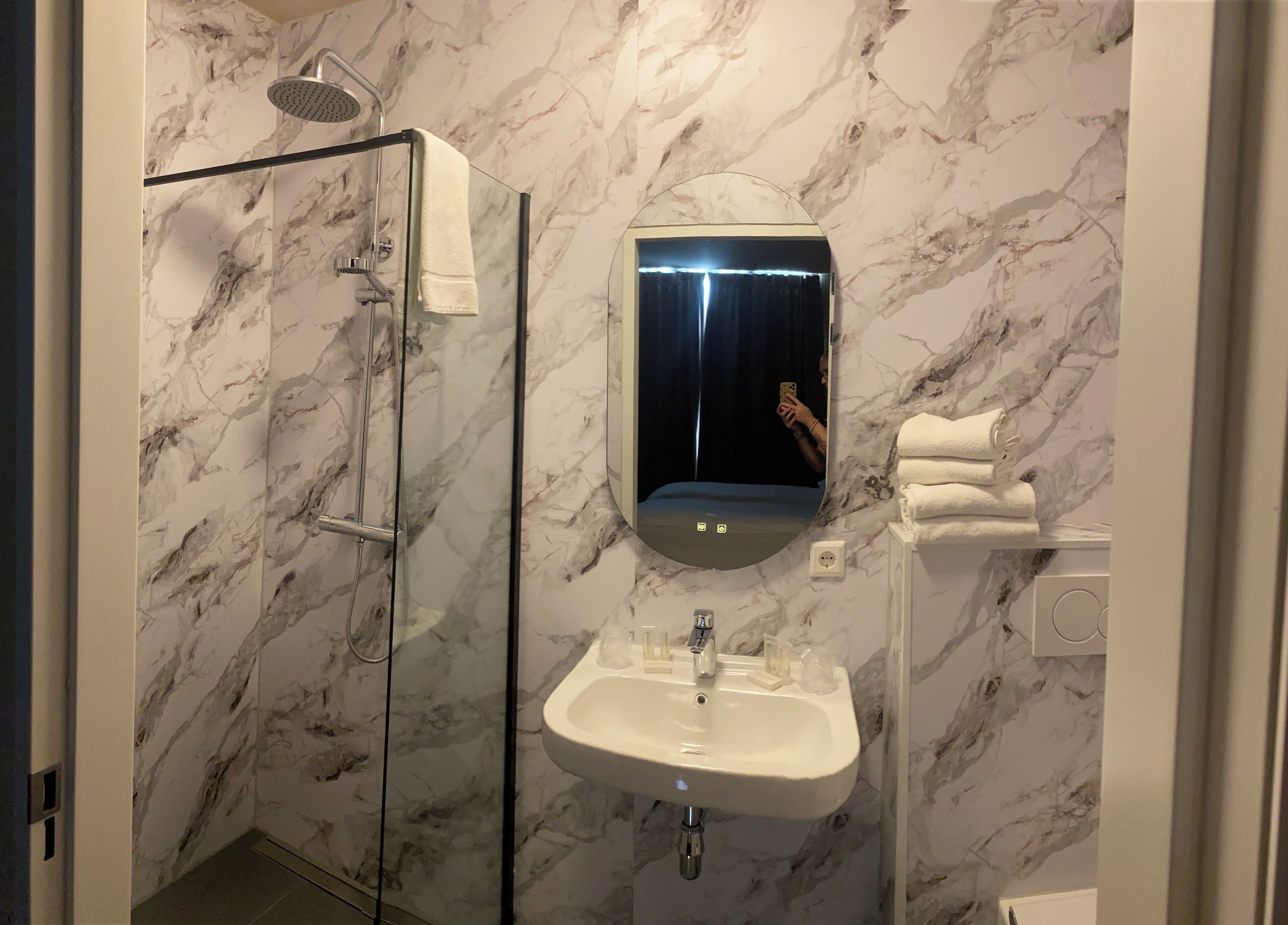 Une salle de bain avec une douche à parois de verre, un lavabo et un miroir.