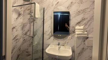 Une salle de bain avec une douche à parois de verre, un lavabo et un miroir.