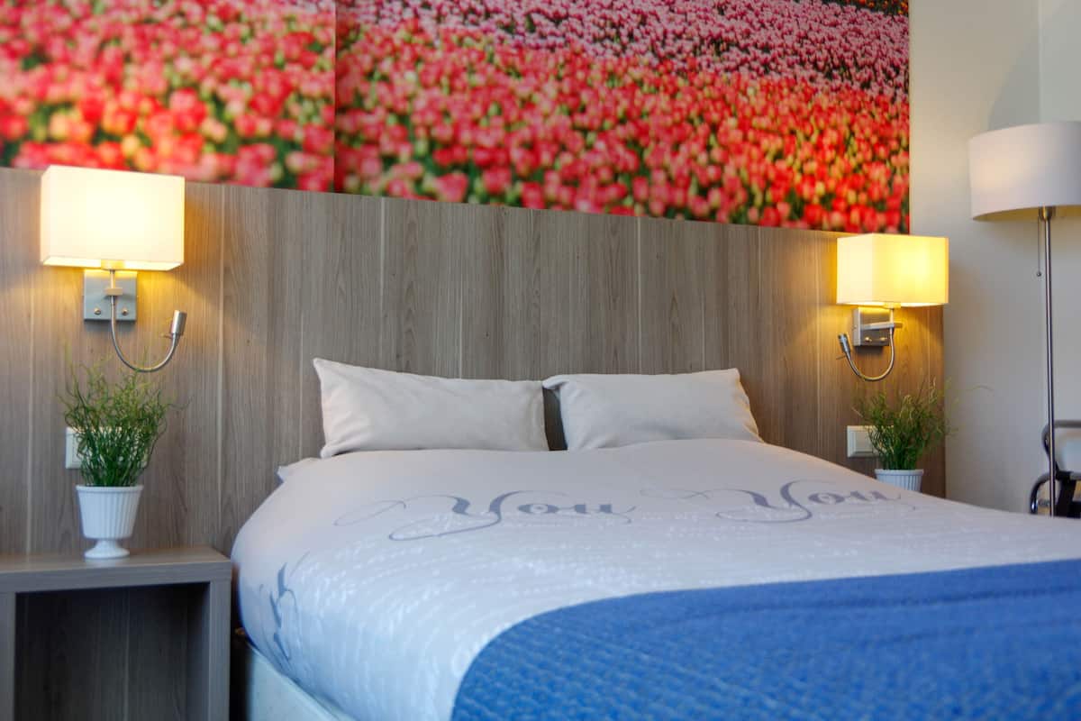 Een hotelkamer met een groot bed, twee bedlampen en een bloemen behang.