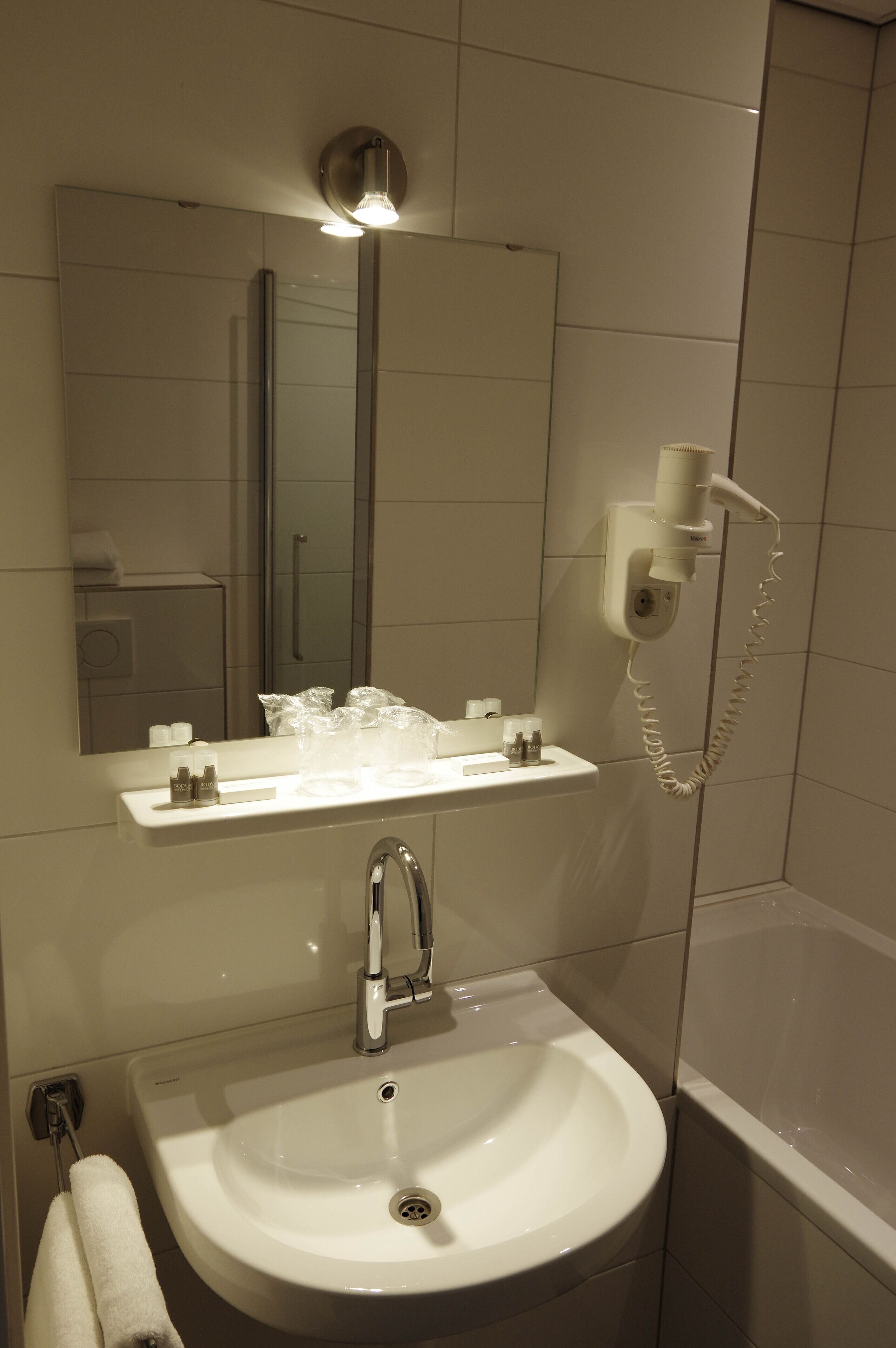 Ein Badezimmer mit Waschbecken, Spiegel und Wandhaartrockner.