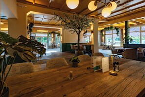 A wooden dining table with a menu, a glass of water, and salt and pepper shakers. - Hotel and Restaurant van Saaze (Kraggenburg)