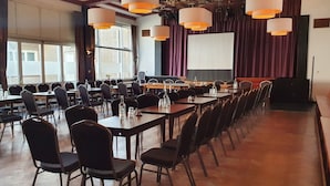 Une salle de conférence avec de longues tables, des chaises et un grand écran.
