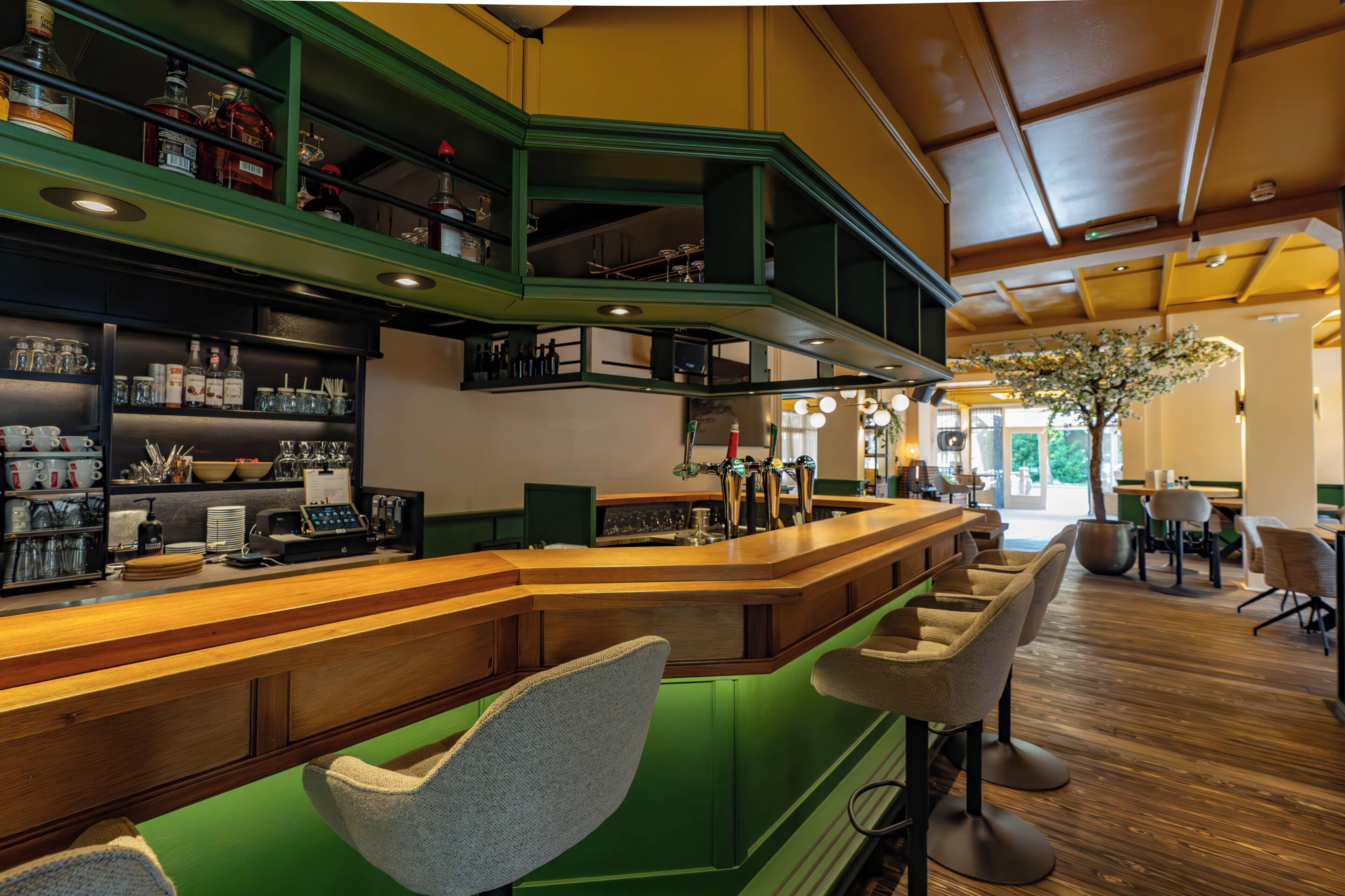 Uma área de bar com balcão, banquetas e prateleiras cheias de garrafas.