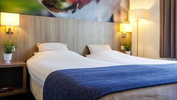 Habitación de hotel con una cama grande, dos lámparas de noche y un televisor montado en la pared.