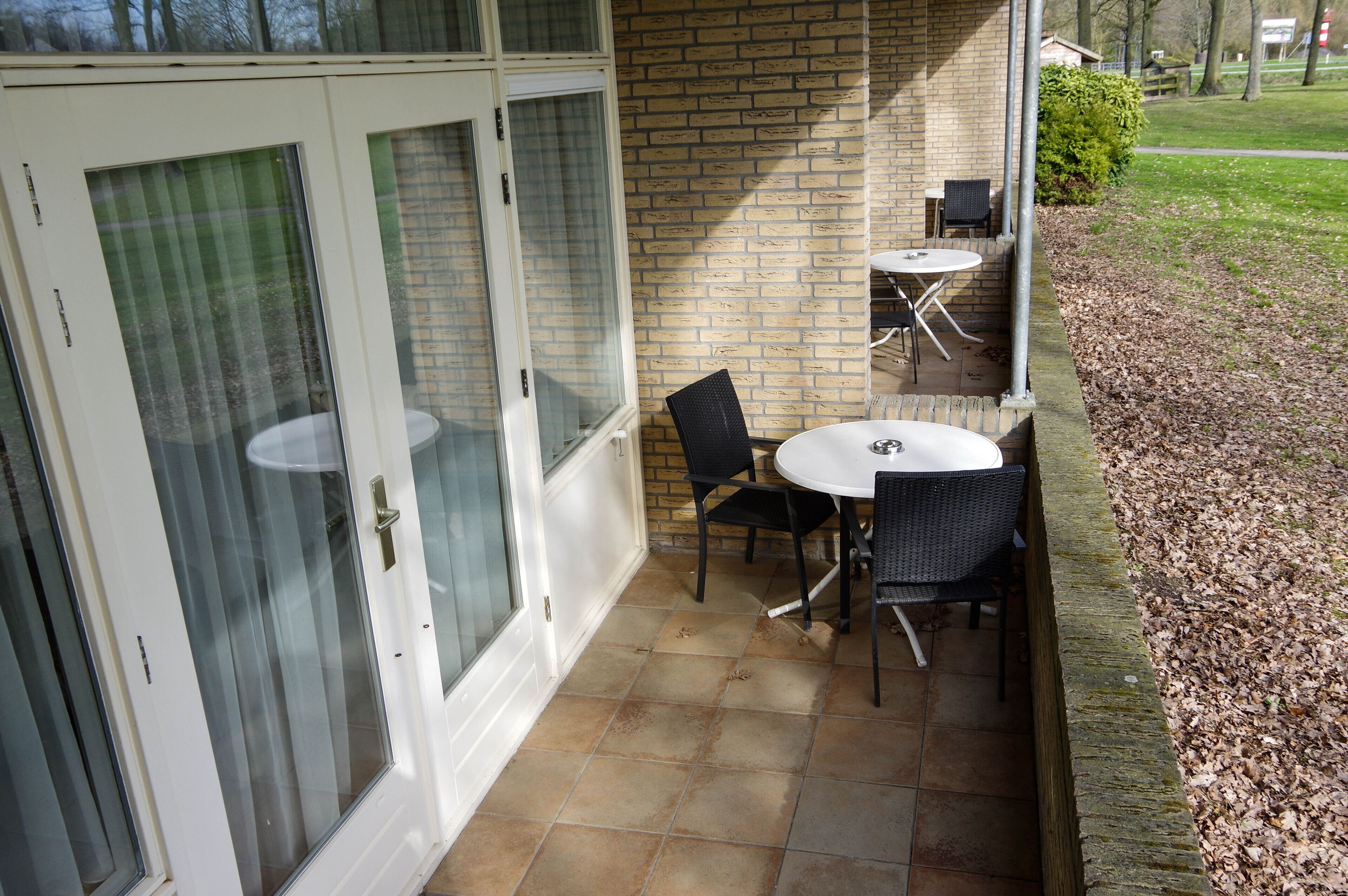 A patio area with a brick wall, a glass door, and a small table with two chairs.