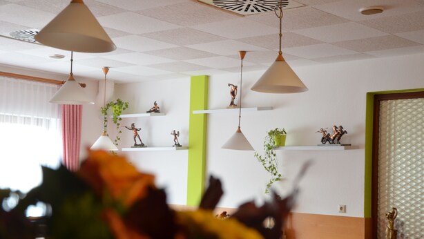 Een modern interieur met hanglampen, planken met decoratieve objecten en een groene accentmuur.