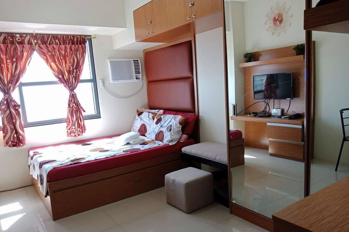 A bedroom with a bed, a desk, a chair, and a TV.