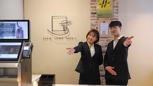 A reception desk at Slow Town Hotel with a digital screen, a cash register, and a small table with a candle. - Slow Town Hotel - Reel (Taipei)