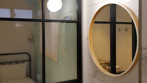 A modern bathroom with a glass partition, a round mirror, and a metal bed frame. - Slow Town Hotel - Reel (Taipei)