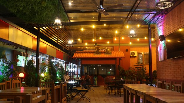Un restaurante con mesas y sillas de madera, una pared de ladrillo y luces colgantes.