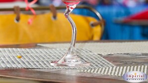 Una copa de martini con una bebida roja sobre una mesa con posavasos.