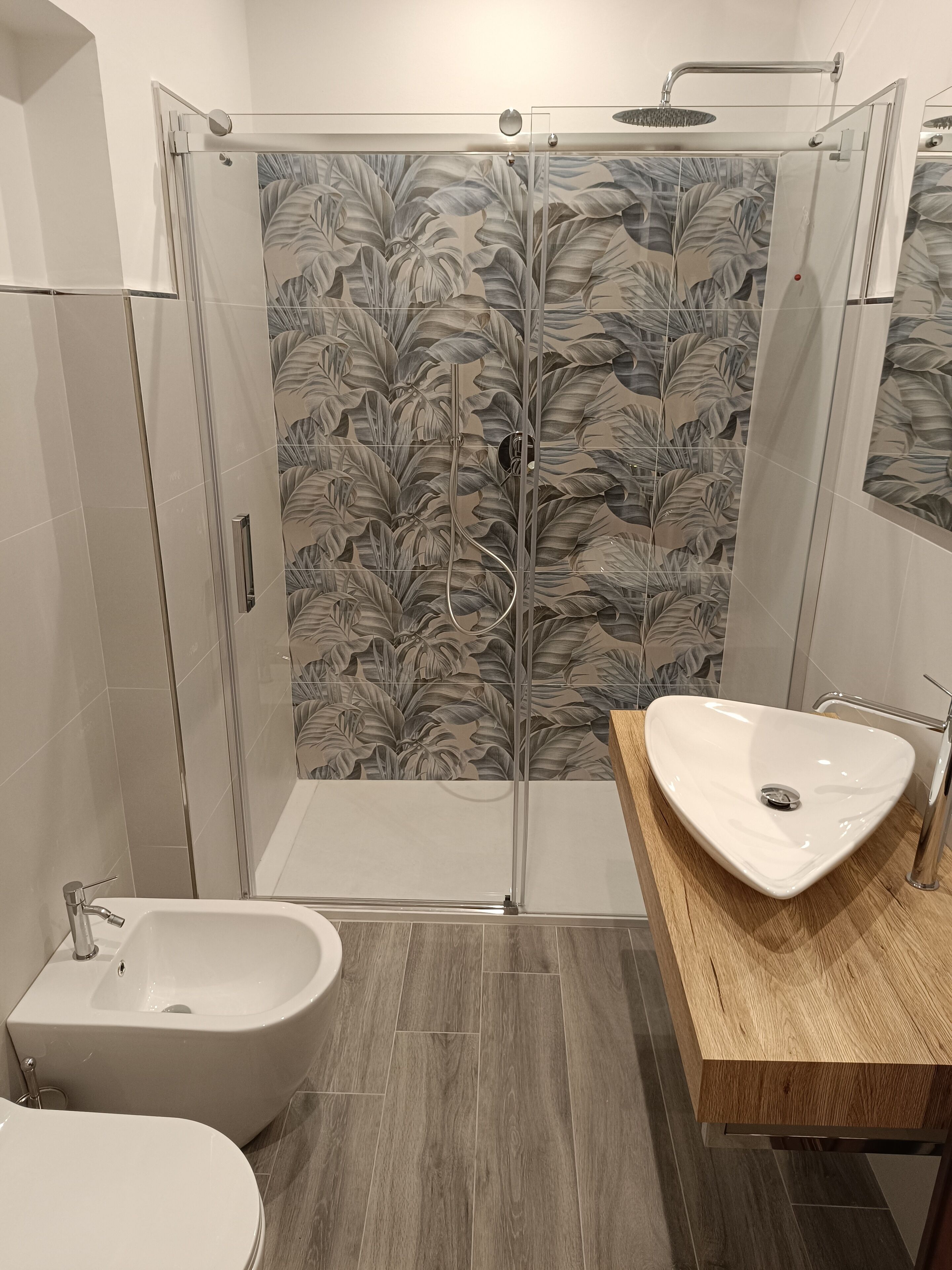 Un baño moderno con ducha envuelta en vidrio, una bañera independiente y un tocador de madera con lavabo.