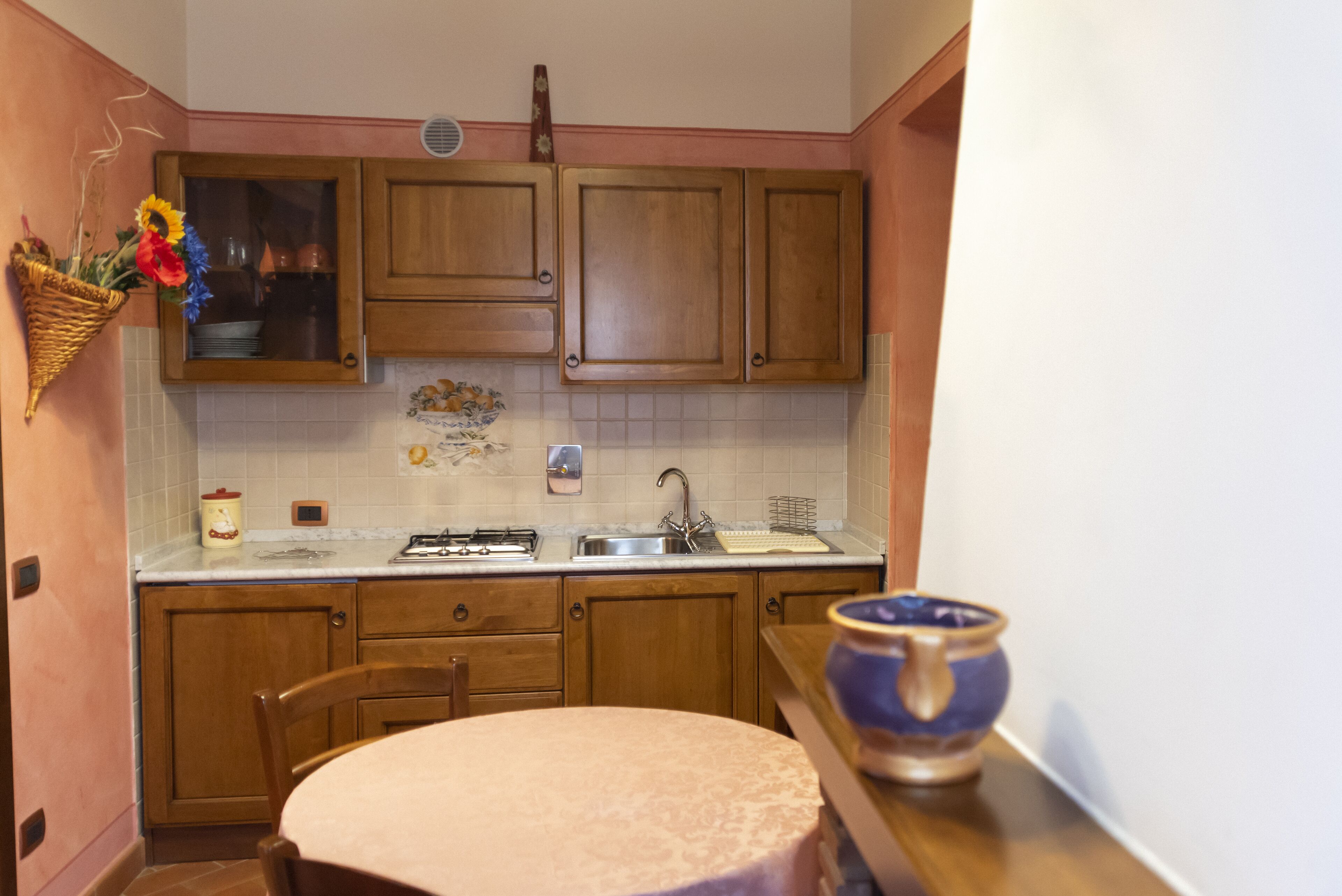 Una cocina con armarios de madera, un lavamanos, una estufa y una mesa de comedor con mantel.