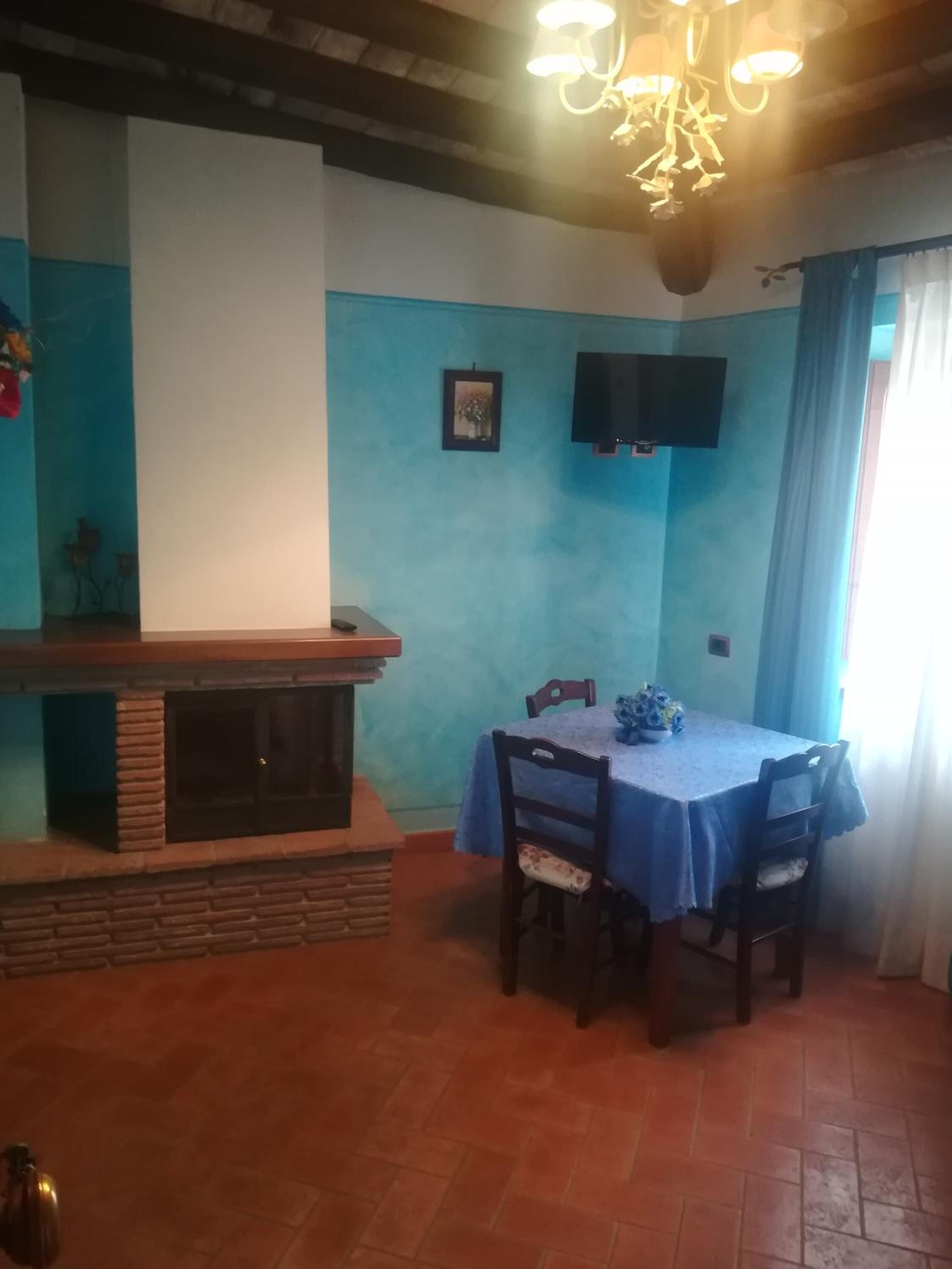 A dining area with a blue table and chairs, a fireplace, and a television mounted on the wall.