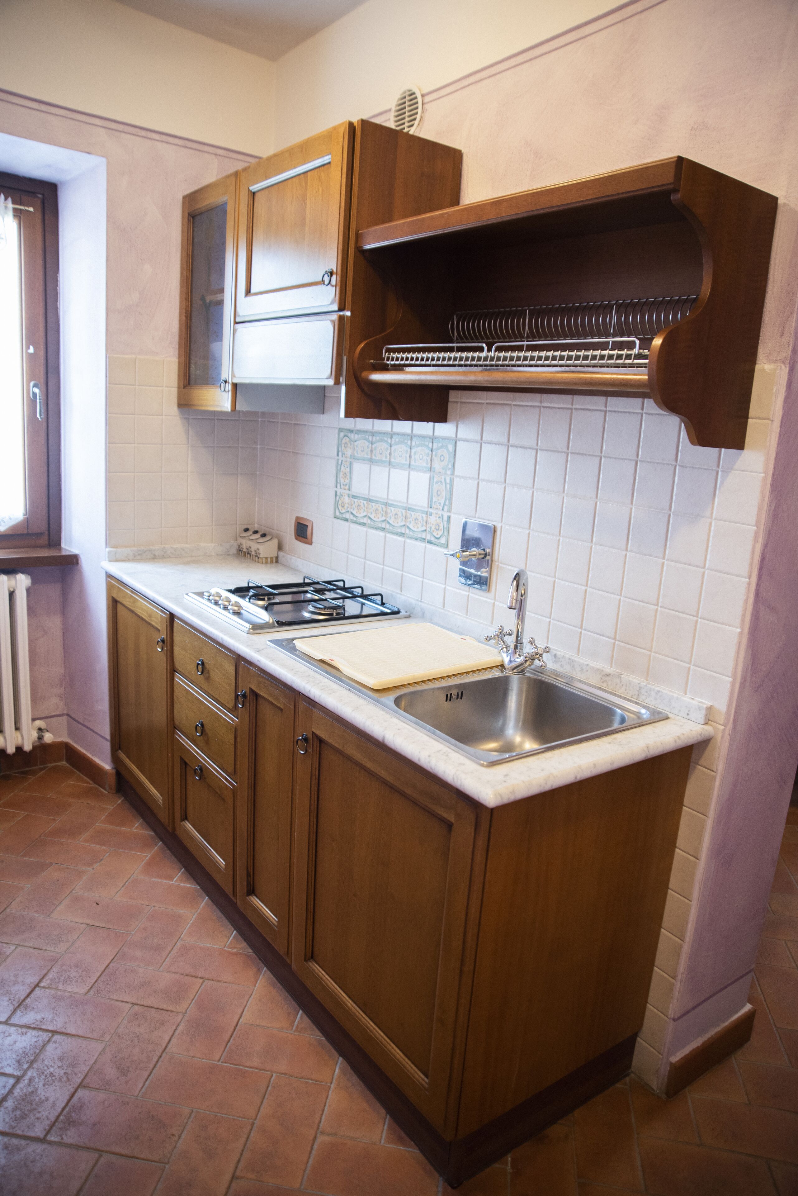 A kitchen with wooden cabinets, a gas stove, a sink, and a tiled backsplash.