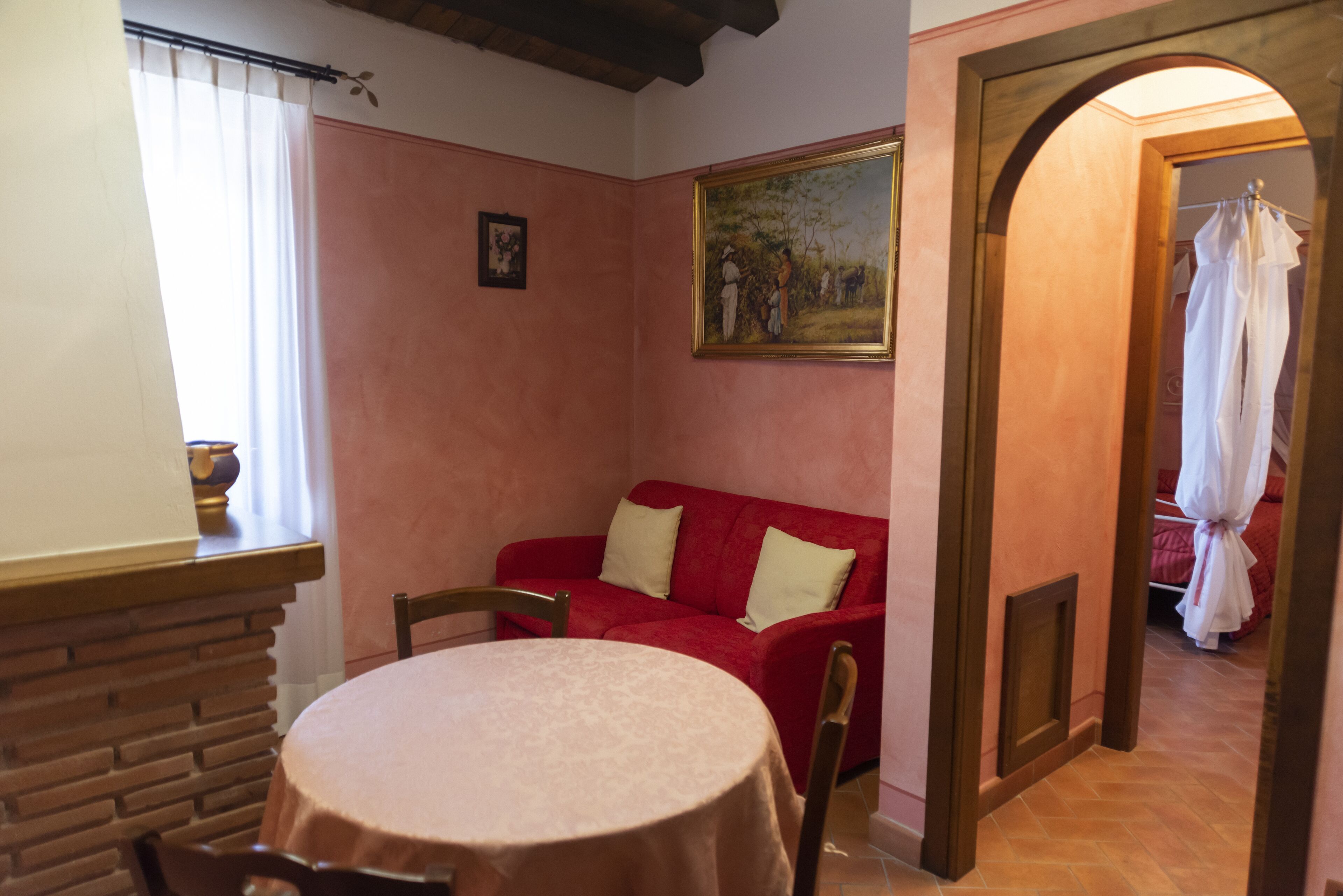 Un ambiente accogliente con un divano rosso, un tavolo rotondo e un quadro appeso al muro.