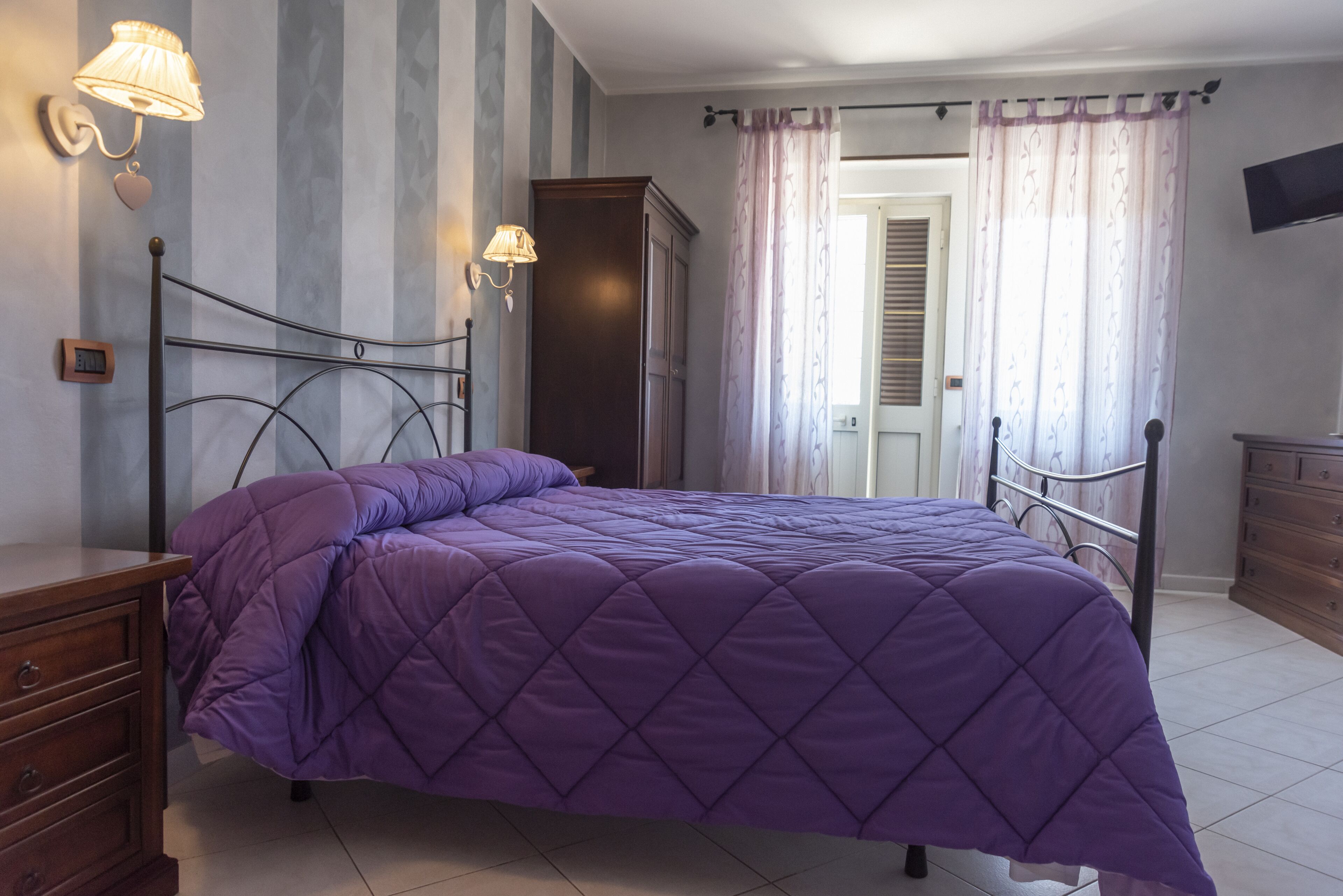 Ein Schlafzimmer mit einem Bett, Nachttischen, einem Kleiderschrank und einem Fernseher.