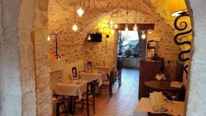 Un restaurant rustique aux murs de pierre, avec des tables en bois et des luminaires suspendus.