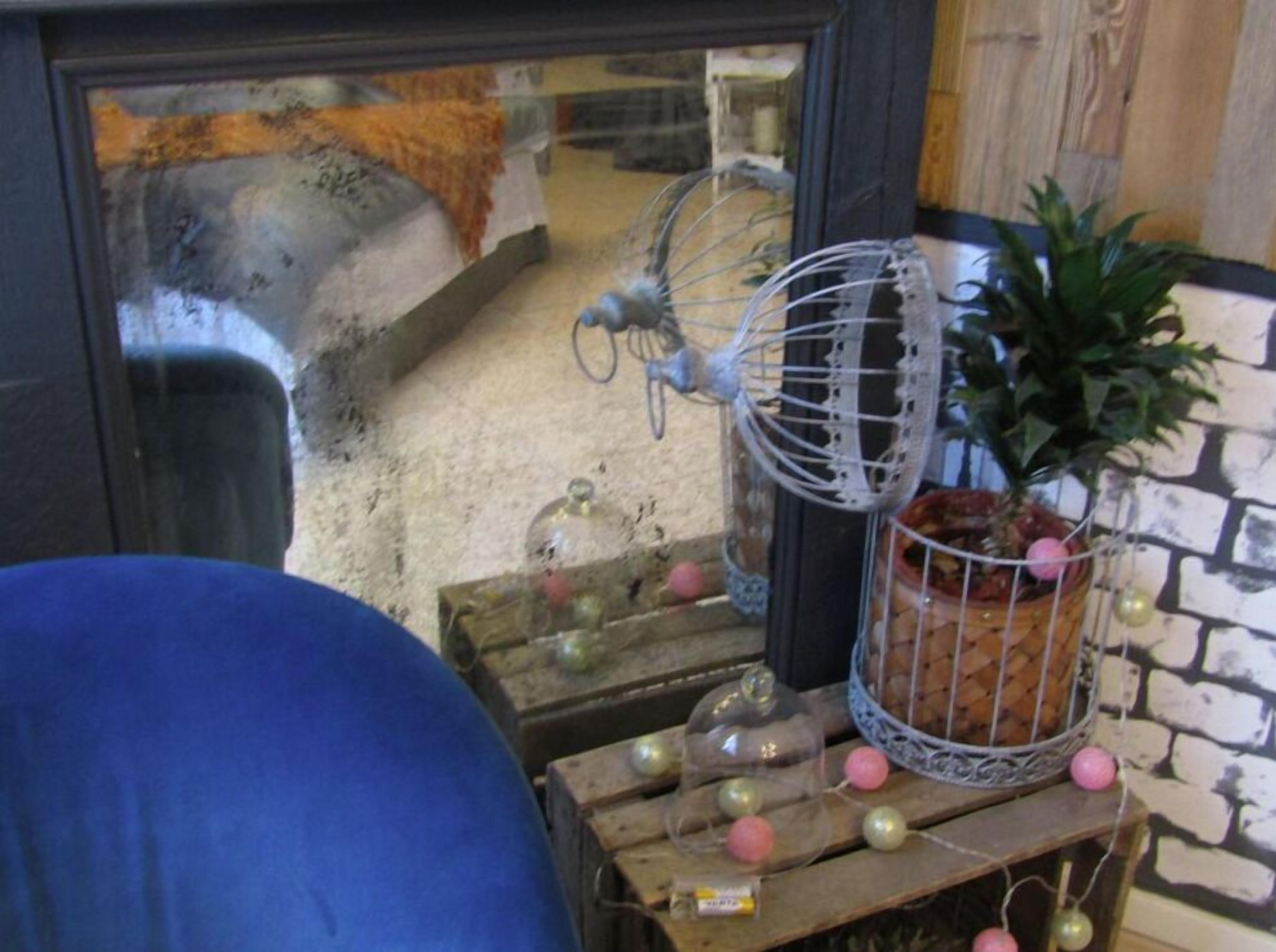 Un intérieur rustique avec une table en bois sur laquelle sont disposés des objets décoratifs, comme des bocaux en verre, un ventilateur en métal et une plante en pot.