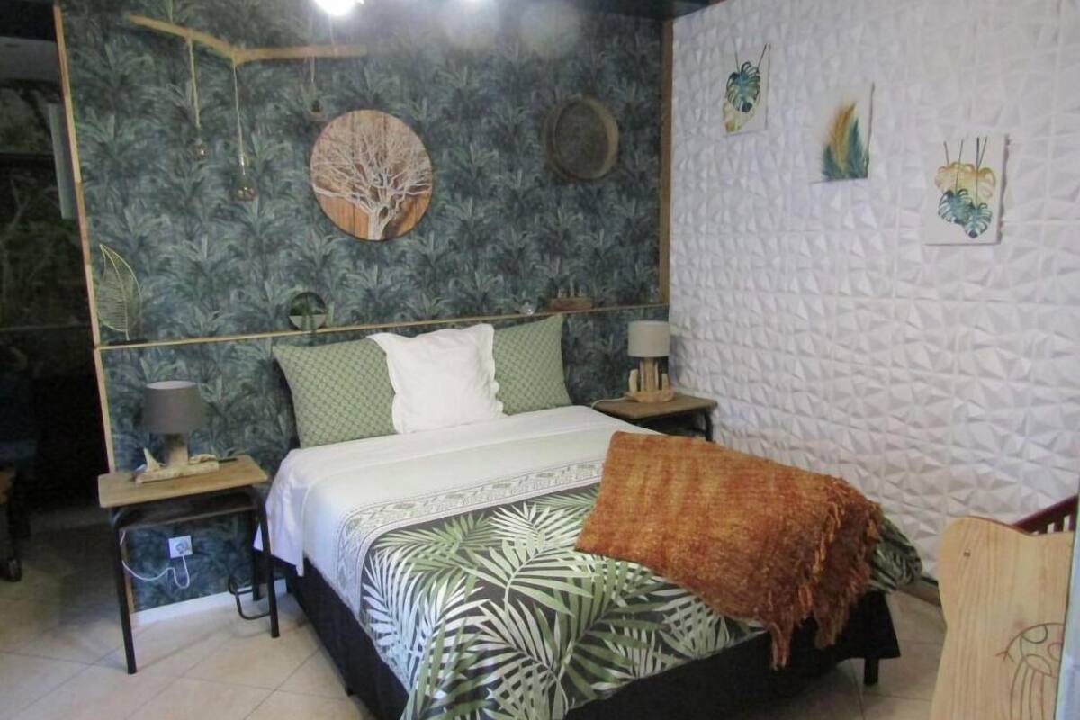 Une chambre à coucher comprenant un lit, deux tables de chevet, une lampe, une horloge murale et une œuvre d’art décorative représentant un arbre.