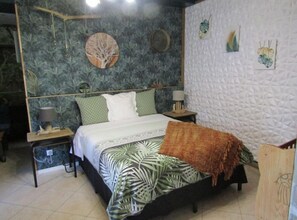 A bedroom with a bed, two nightstands, a lamp, a wall clock, and a decorative tree artwork. - Au Nid Du Thil  (Beauvais)