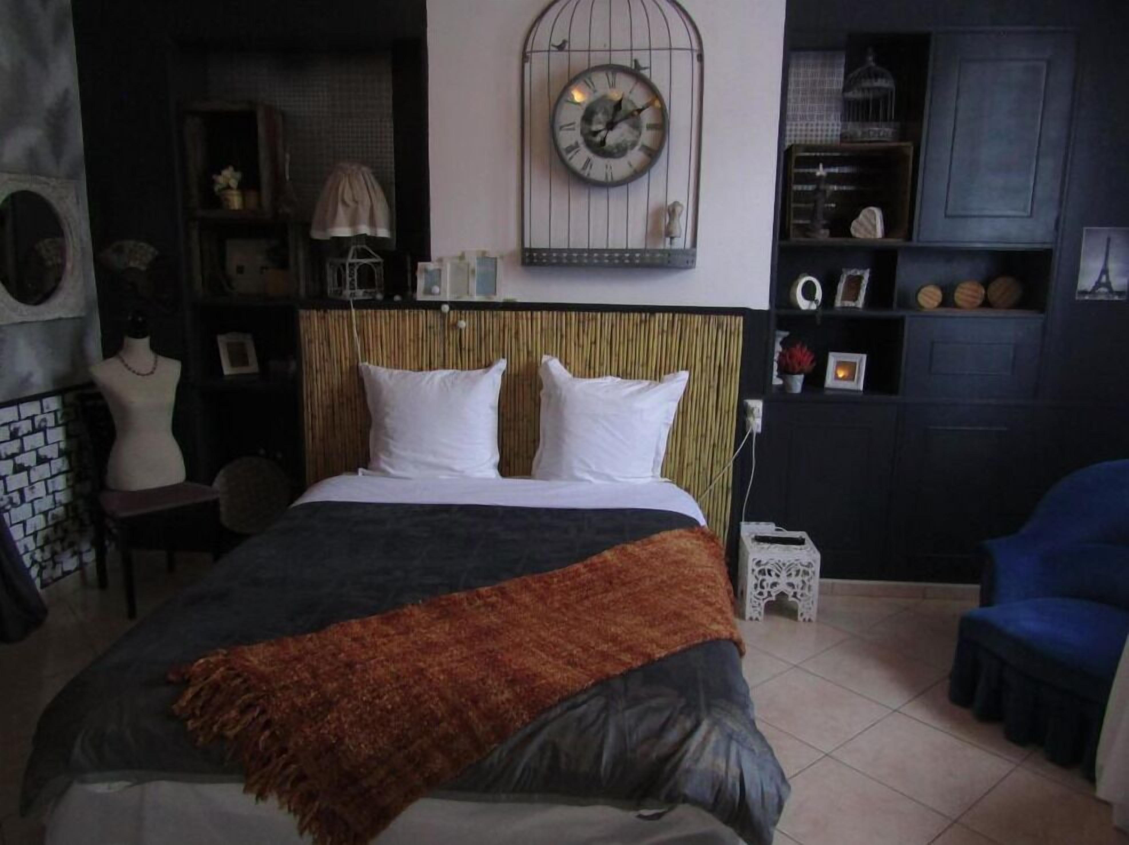 Un dormitorio con una cama, un reloj en la pared y una silla azul.