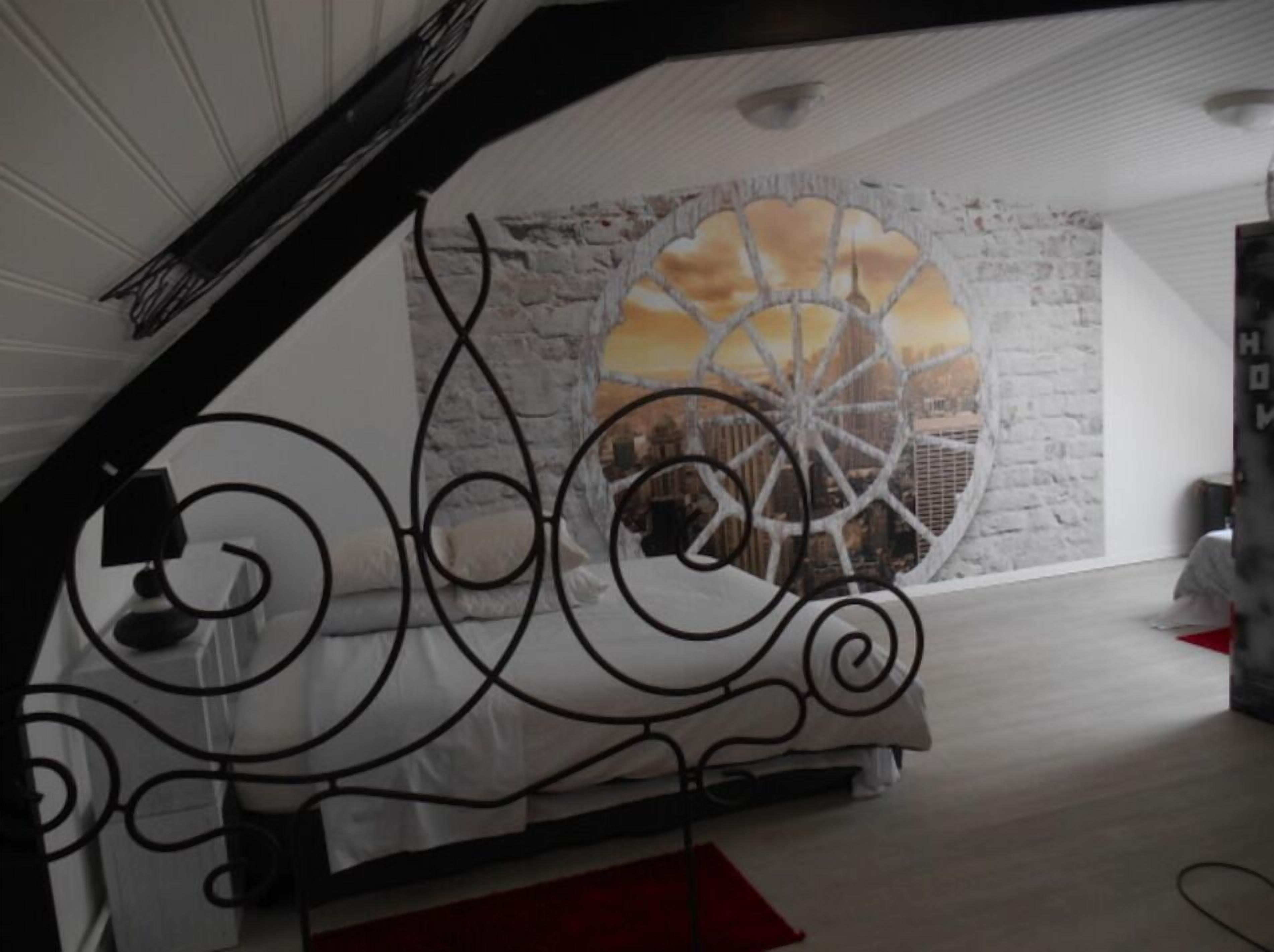 Una habitación con techo inclinado, un ventanal con vistas a una noria y una barandilla decorativa de metal.