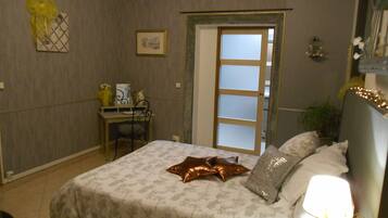A bedroom with a bed, bedside table, chair, and a door leading to another room.