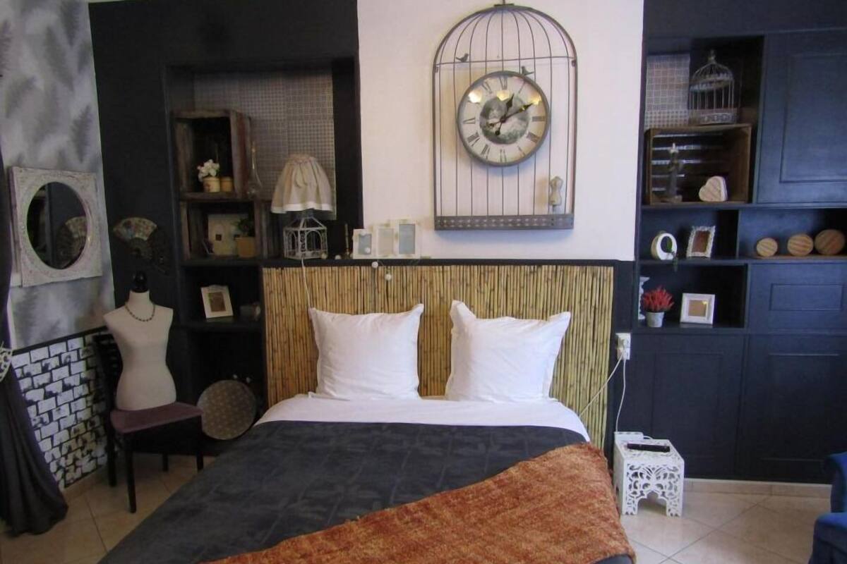 Une chambre à coucher avec un lit, une horloge et une étagère ornée d’objets décoratifs.