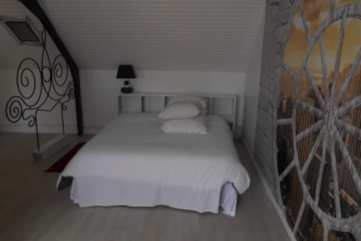Une chambre à coucher avec un lit, une table de chevet, une lampe et un mur décoratif.