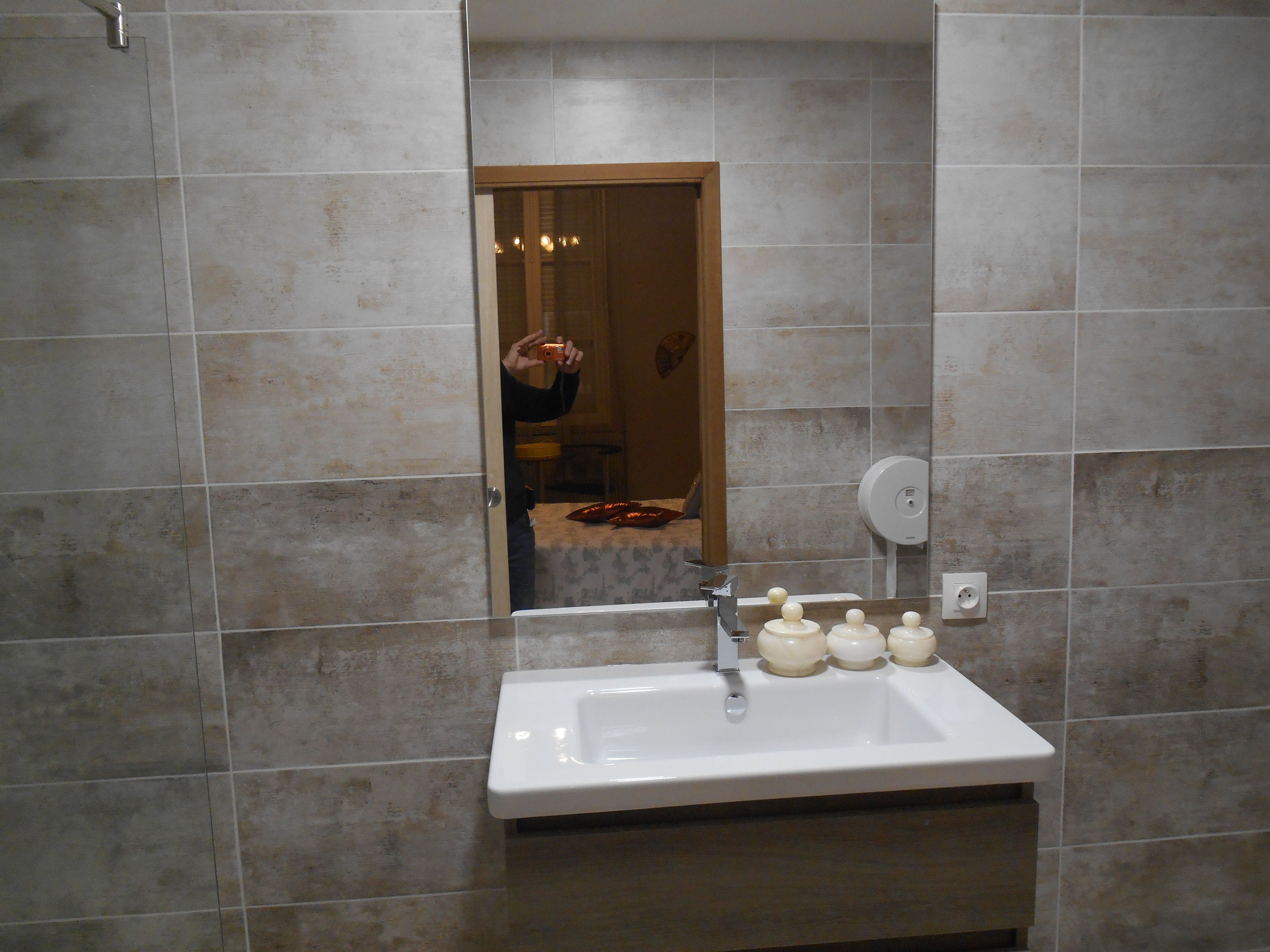 Un baño con lavamanos, espejo y paredes de azulejos.