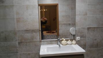 Un baño con lavamanos, espejo y paredes de azulejos.