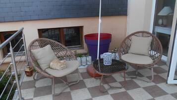 Een terras met rieten stoelen en een geruite vloer.