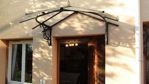 Un ingresso di un edificio con portico coperto, una porta con luce e una finestra con tenda.