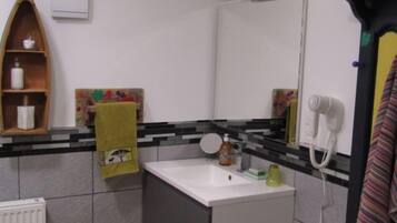 A bathroom with a white sink, a mirror, a hairdryer, and a towel rack.