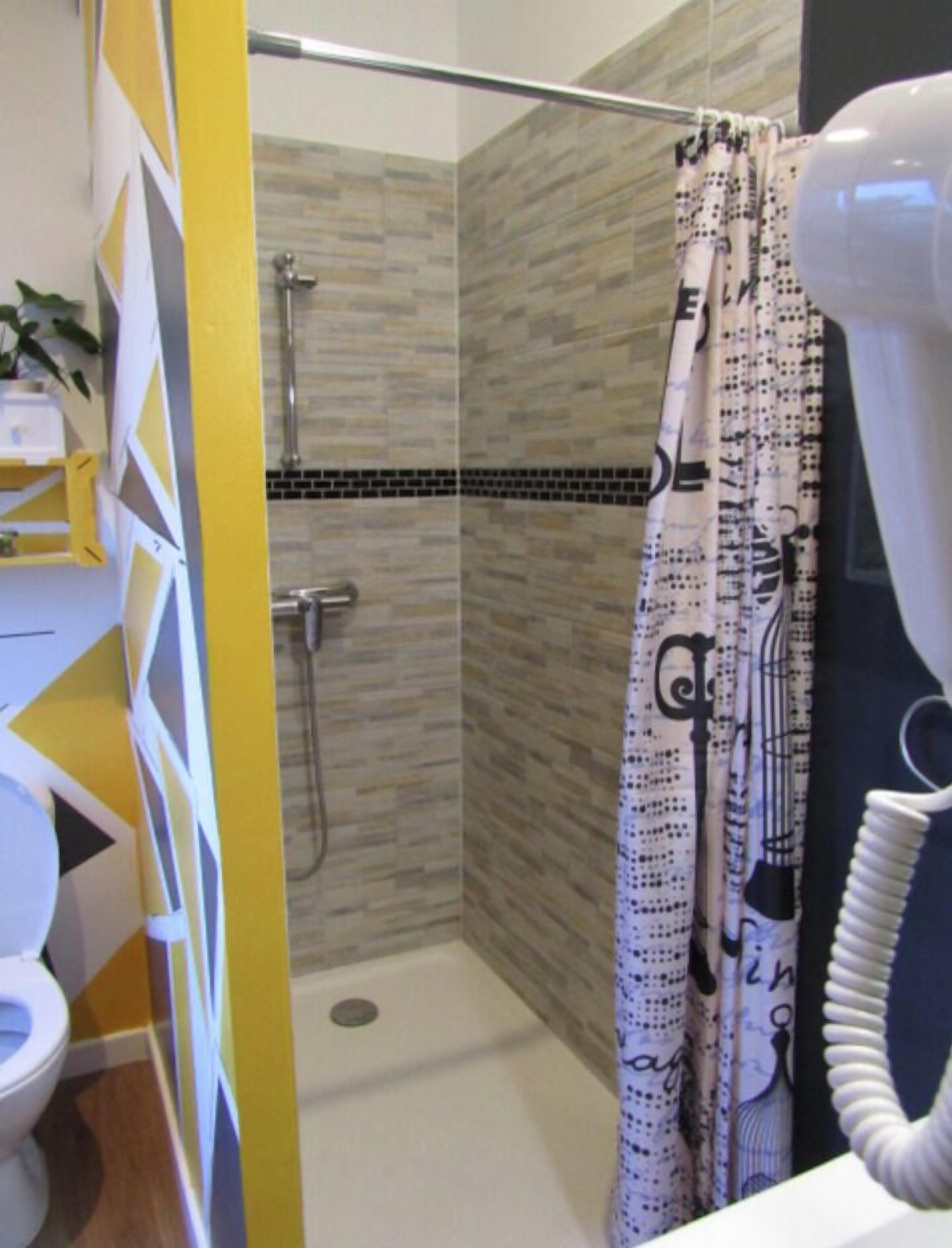 A bathroom with a shower, toilet, and a towel rack.
