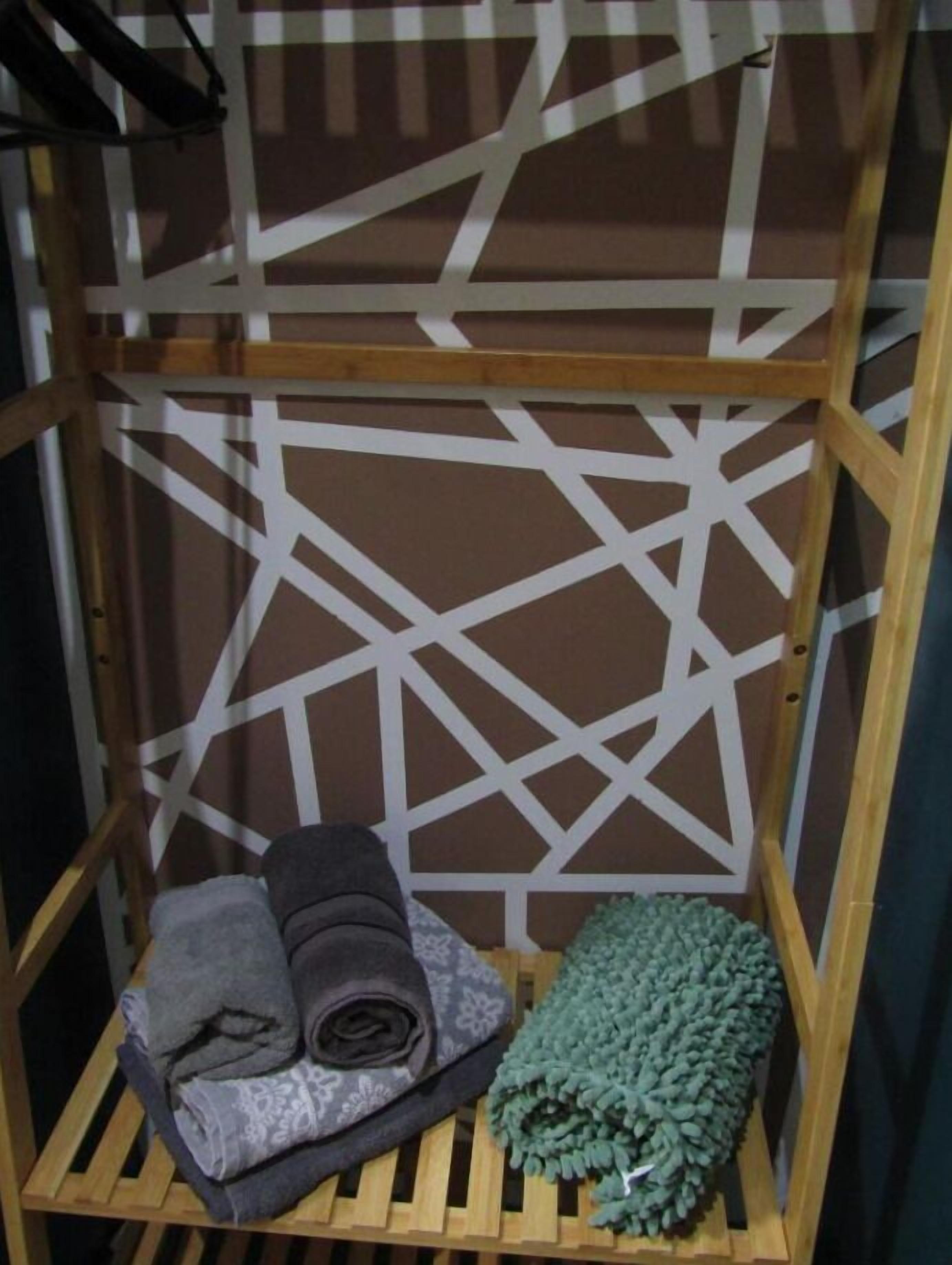 A wooden shelf unit with geometric patterns, holding folded blankets and a green textured item.