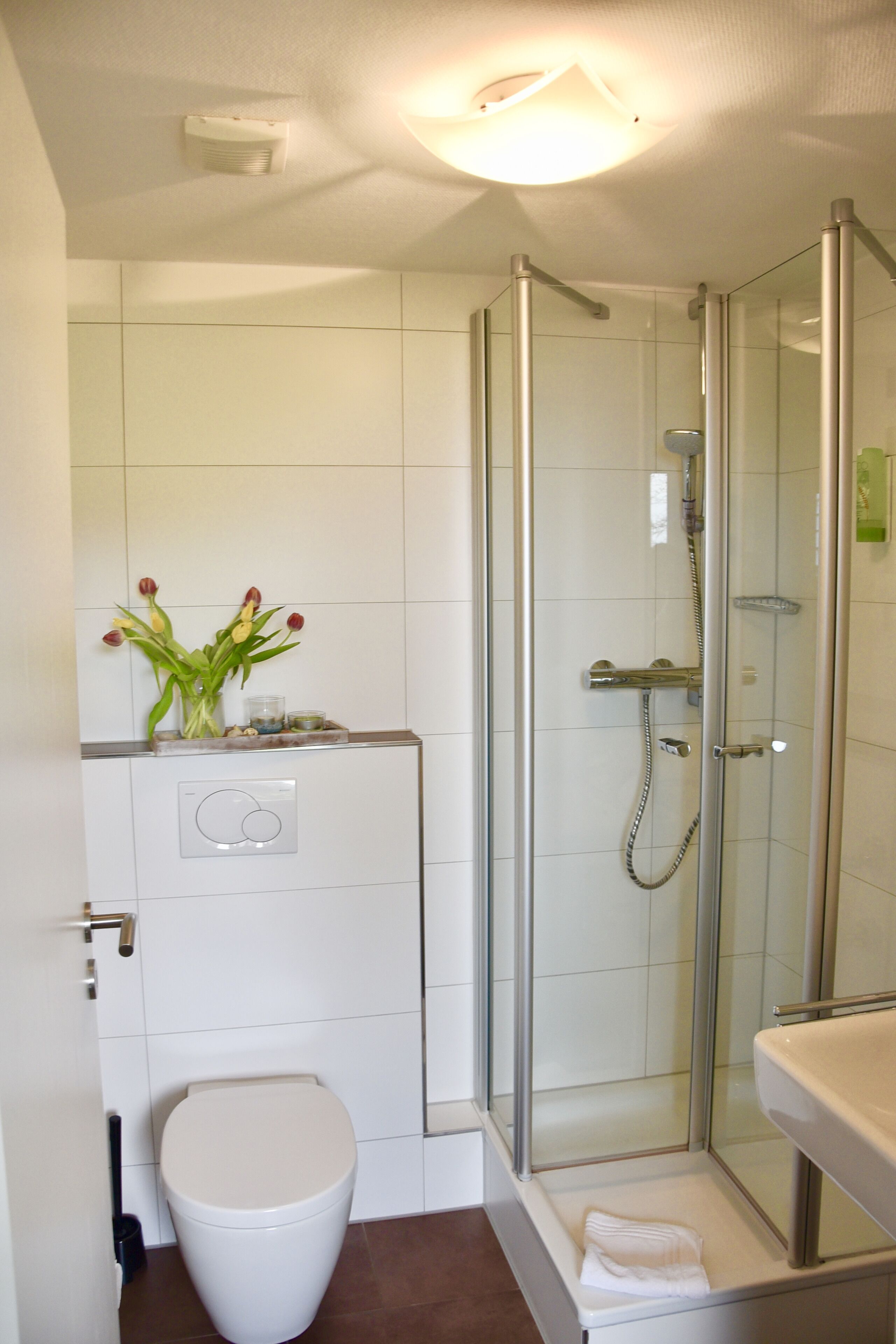 Un baño con inodoro, cabina de ducha de vidrio y lavamanos.
