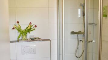 Un baño con inodoro, cabina de ducha de vidrio y lavamanos.