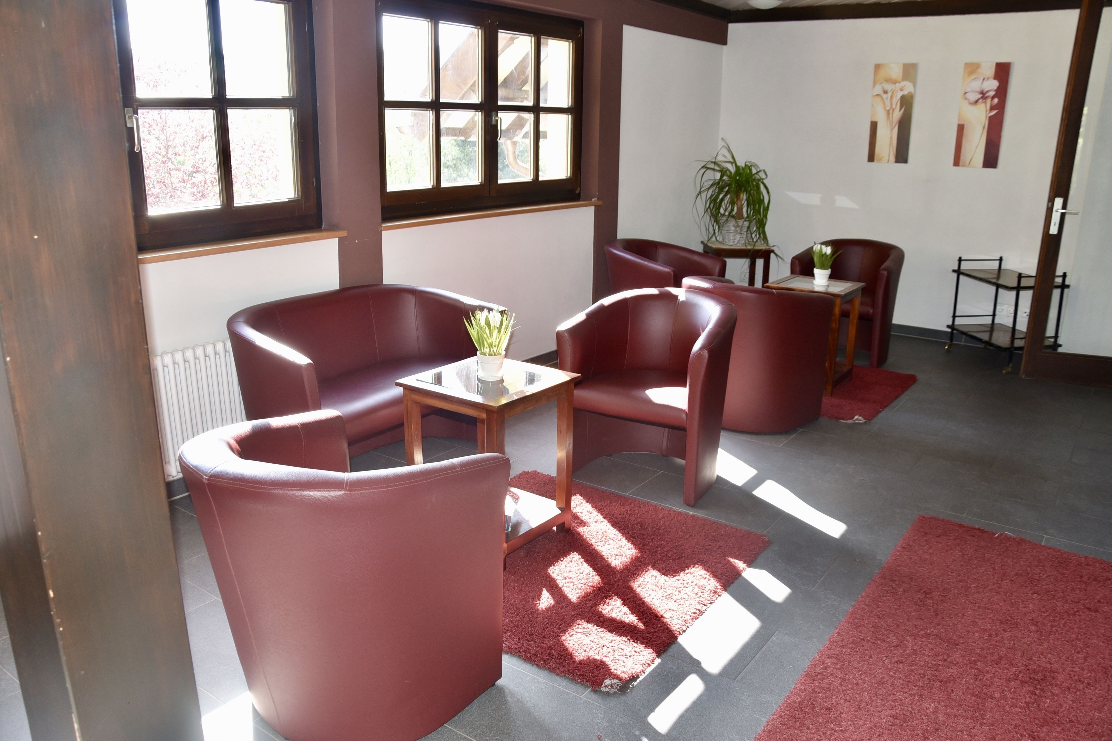 Une pièce avec des fauteuils en cuir rouge, une petite table et une plante en pot.