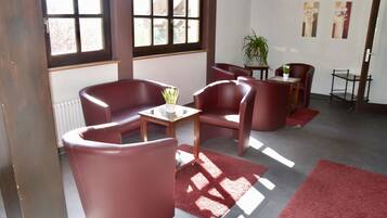 Une pièce avec des fauteuils en cuir rouge, une petite table et une plante en pot.