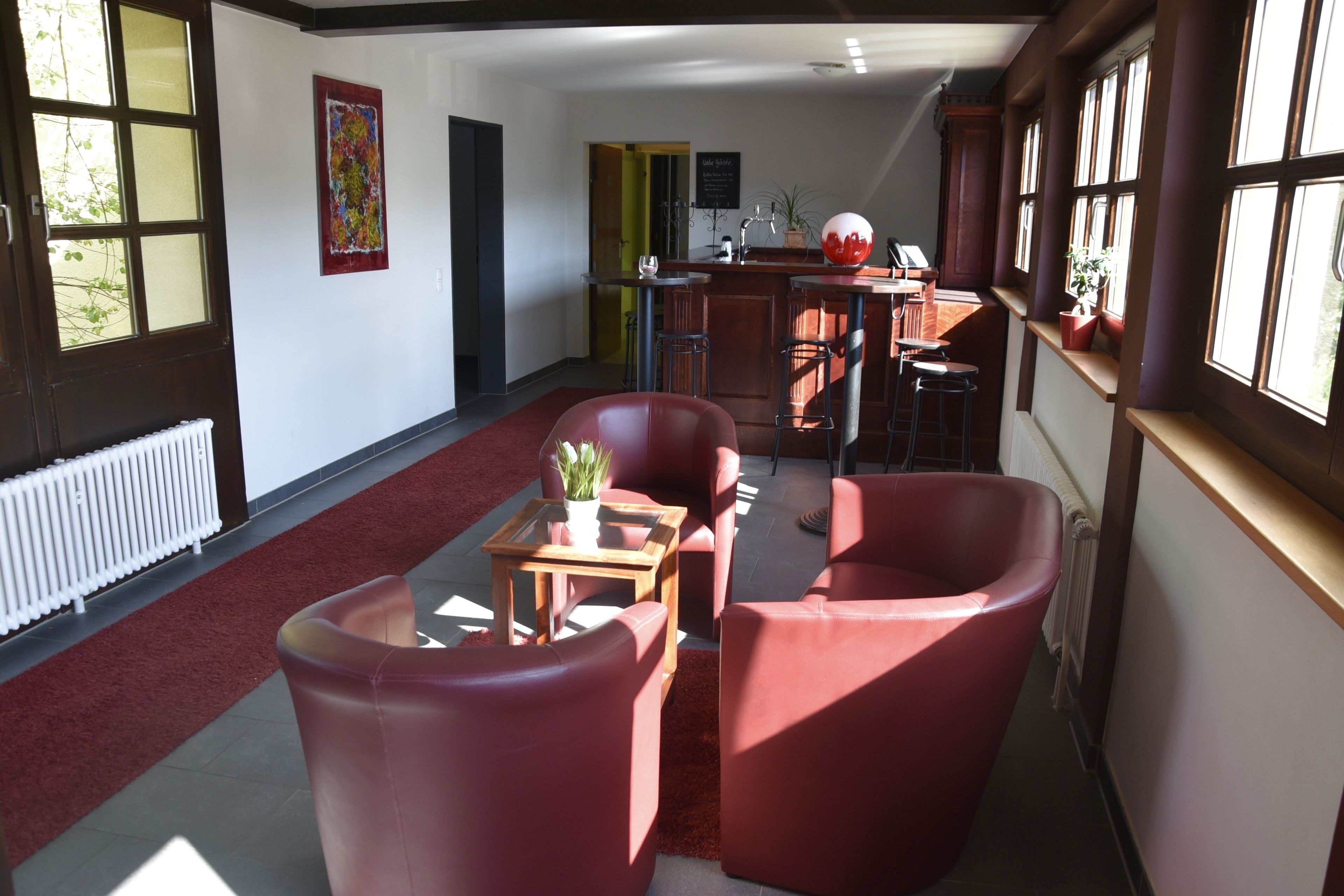 A spacious living area with red leather chairs, a wooden coffee table, and a kitchen in the background.