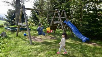 Un parque infantil con columpios, tobogán y zona de escalada.