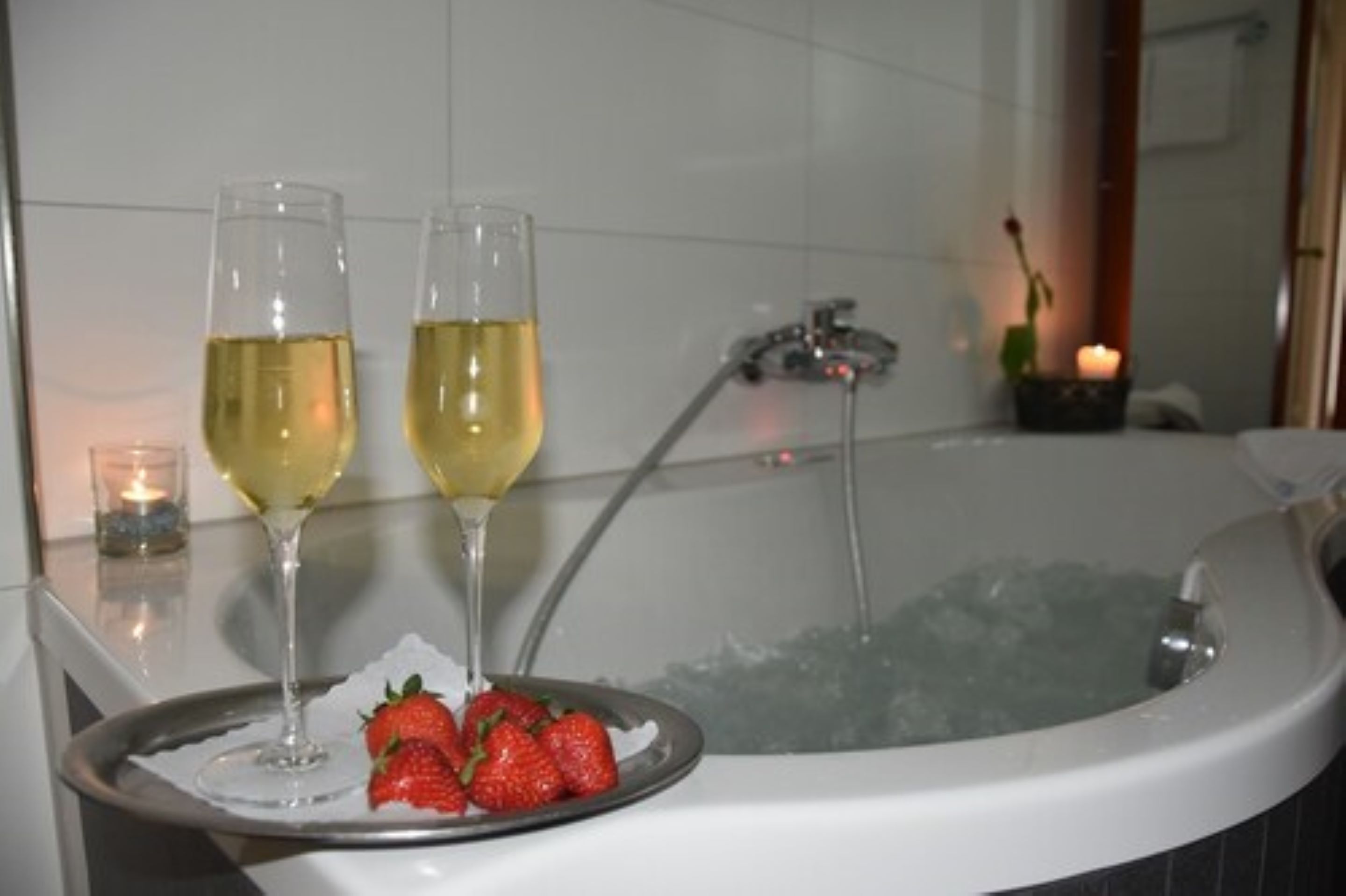 Una bañera con dos copas de vino blanco y un plato de fresas.