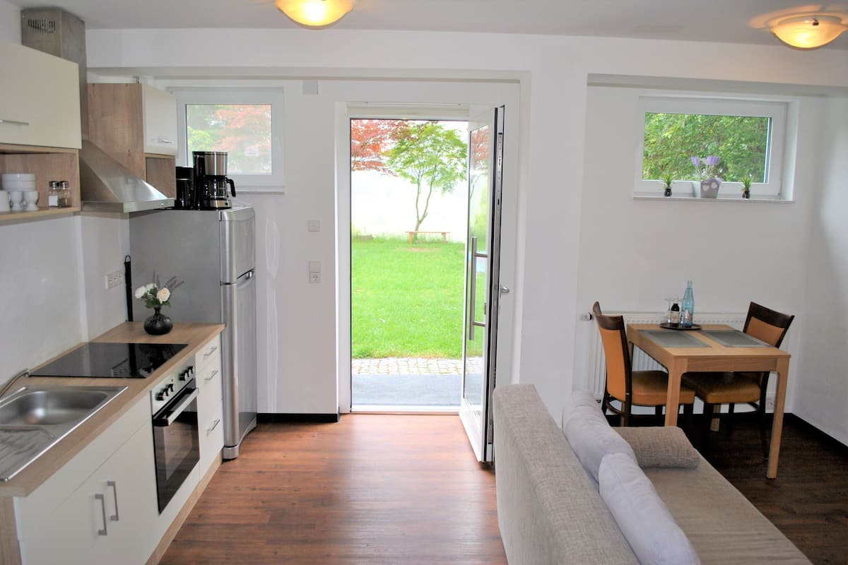 A modern kitchen with a built-in oven and a dining area with a wooden table and chairs.