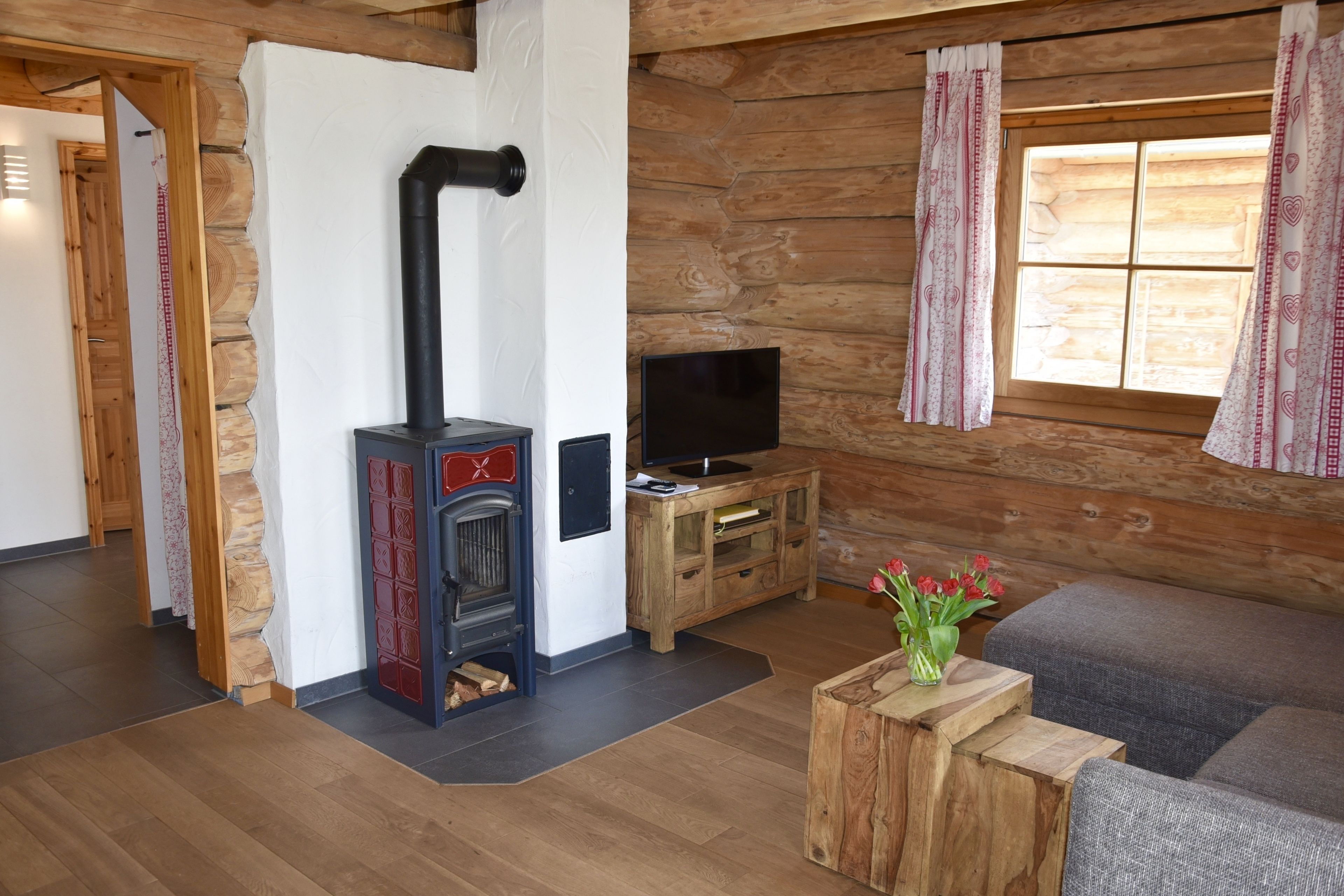 Een gezellig interieur van een blokhut met een open haard, houten meubels en een televisie.