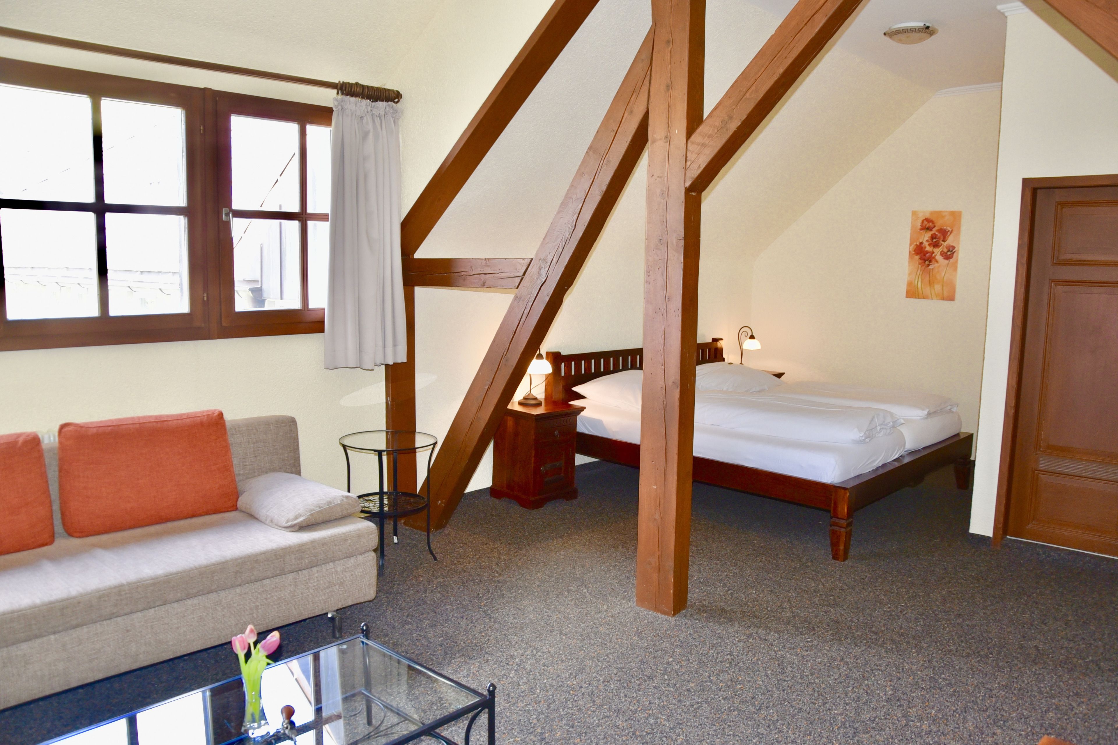 Un dormitorio con cama, sofá y una mesa de centro de vidrio.