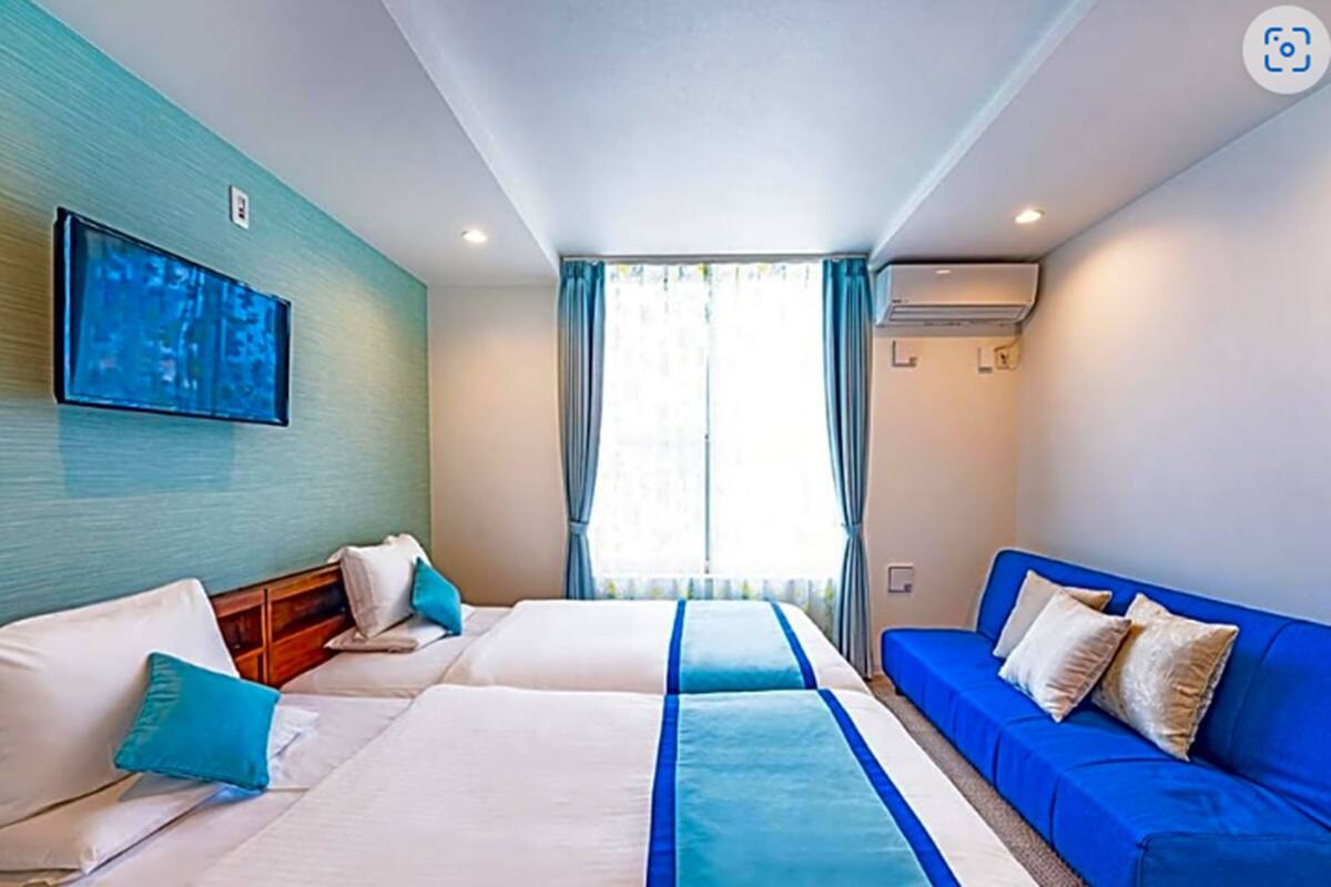 Une chambre d’hôtel avec deux lits, une télévision et une fenêtre avec des rideaux.