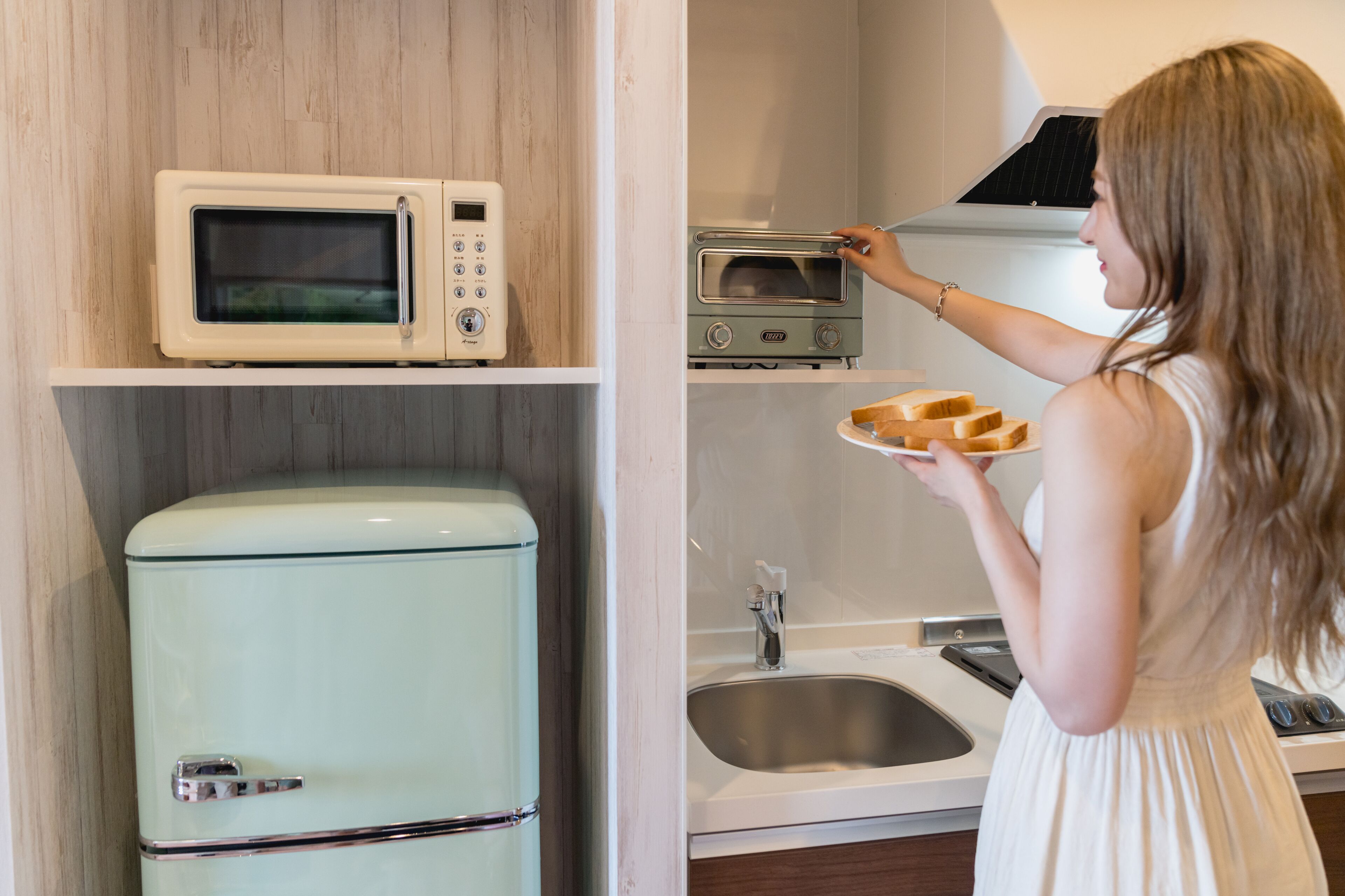 A kitchen with a vintage refrigerator, a microwave, a toaster oven, and a sink.